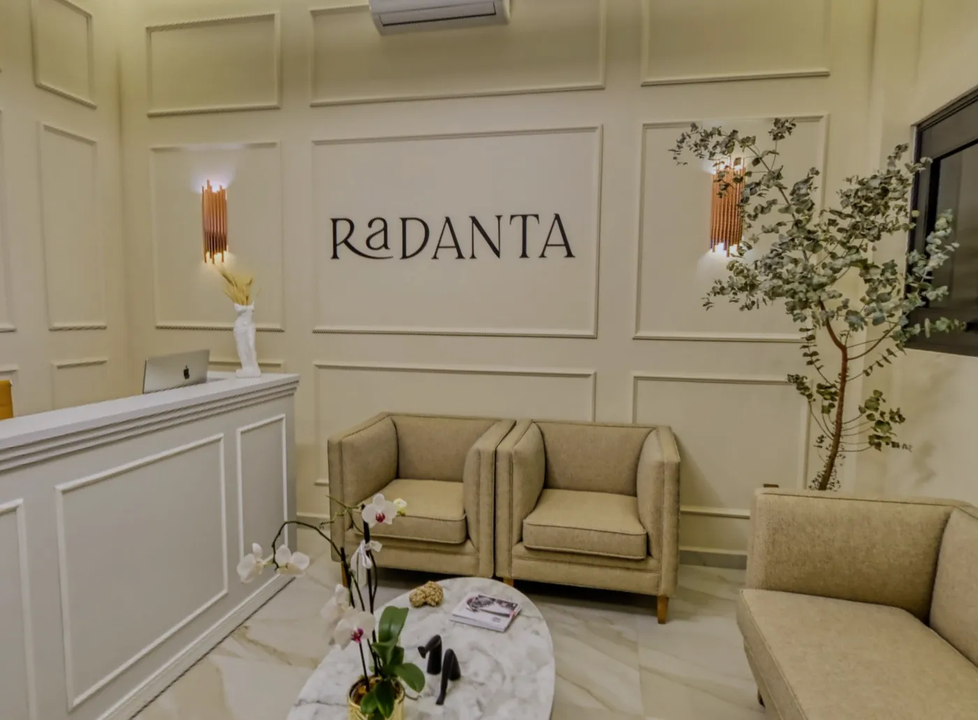 The reception: the sign between mouldings, the brass sconces, the white front desk and two linen armchairs.