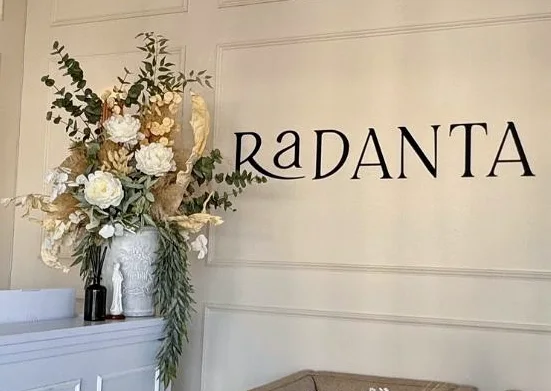 The RaDANTA sign on the moulded reception wall, beside an arrangement of pale flowers.